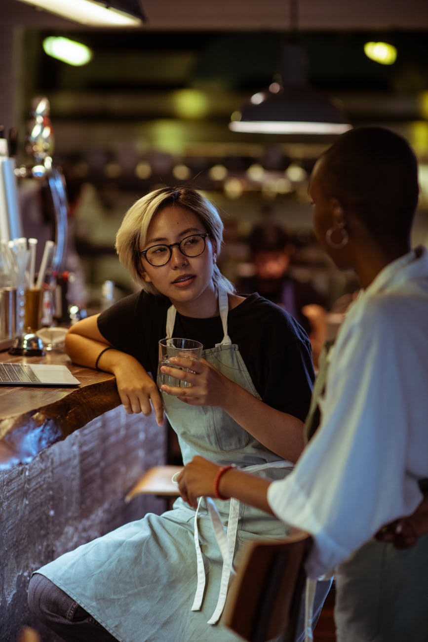 bar workers in aprons chatting near bar counter